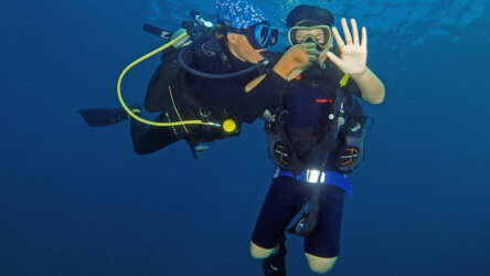 a padi instructor assisting a scuba diving student equalise their ears